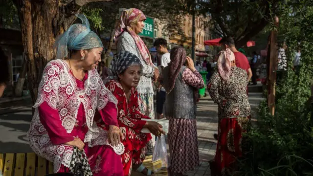 穿着傳統服飾的維吾爾婦女在新疆西部的喀什街頭,觀看維吾爾舞蹈表演。