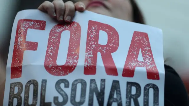 Mulher segura cartaz que diz: Fora Bolsonaro