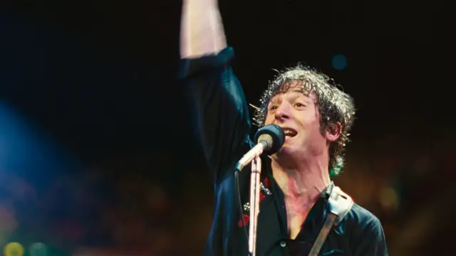 Кадр із фільму "Спрінгстін: Врятуй мене від невідомого" - співак на сцені біля мікрофона підняв руку вгору