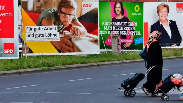 Almanya'da seçim posterlerinin önünden geçen bir Türk kadın