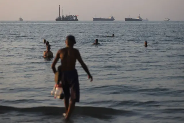 In this picture obtained from Iran's ISNA news agency on June 8, 2026, residents take a dip as cargo and commercial vessels lie at anchor in the Strait of Hormuz off Bandar Abbas.

2026 ජුනි 8 වන දින ඉරානයේ ISNA ප්‍රවෘත්ති ඒජන්සියෙන් ලබාගත් මෙම පින්තූරයේ, බන්ඩාර් අබ්බාස් අසල හෝමූස් සමුද්‍ර සන්ධියේ නැංගුරම් ලා ඇති භාණ්ඩ හා වෙළෙඳ නෞකා දැක ගත හැකි අතර ඇතැම් ඉරාන වැසියන් මුහුදු ජලයේ නාන අයුරු දක්නට ලැබේ.
