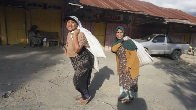 Potret dua orang perempuan di Kampung Bah, Kecamatan Ketol, Kabupaten Aceh Tengah saat memanggul bantuan dari pemerintah desa.