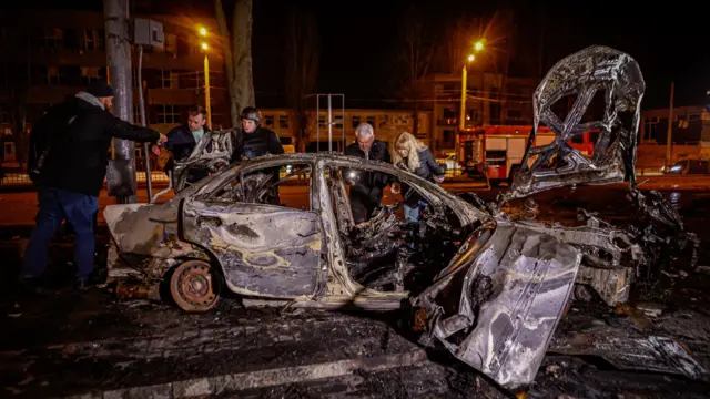 أشخاص يتفقدون سيارة دُمرت بطائرة روسية مُسيّرة في وسط خاركيف، أوكرانيا، في ٢٩ مارس/آذار ٢٠٢٥.