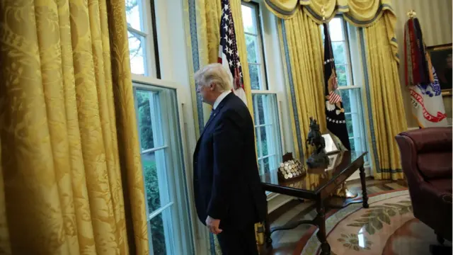 O presidente americano Donald Trump olha pela janela da Casa Branca