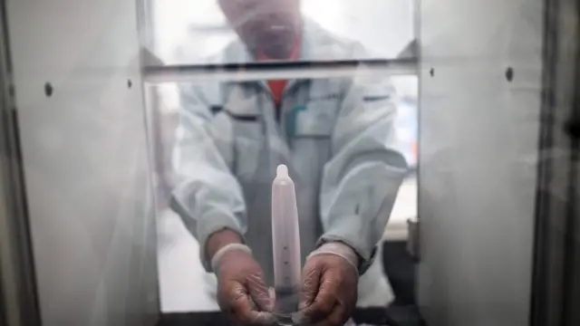 Un empleado del fabricante japonés de condones Sagami Rubber Industries pone un condón en una máquina para probar su resistencia llenándolo de aire.