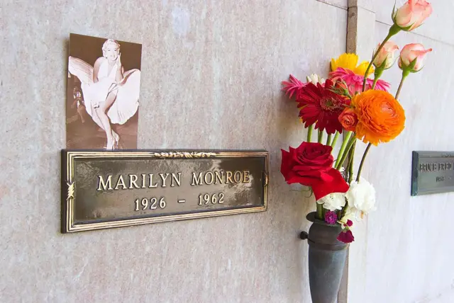 El nicho de Marilyn Monroe, con una placa con su nombre y las fechas 1926-1962. Hay una foto de ella y un ramo de flores