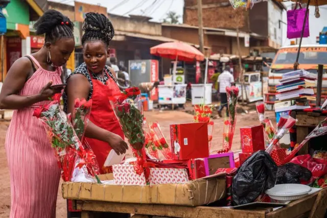 Wasu mata suna tattaunawa a yayin da suke kallon furanni a wata kasuwa a Kampala, Uganda