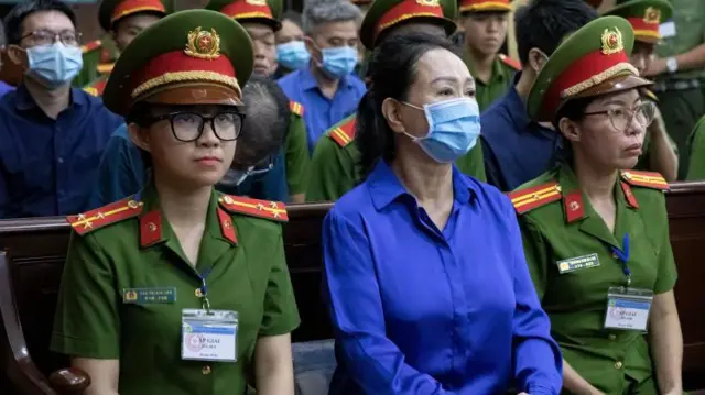 Truong My Lan, chairwoman of Van Thinh Phat Holdings, second left, at the Ho Chi Minh City People's Court in Ho Chi Minh City, Vietnam, on Thursday, Sept. 19, 2024. She is dressed in a blue shirt and has a facemask on. Sat beside her are two women in military uniform.