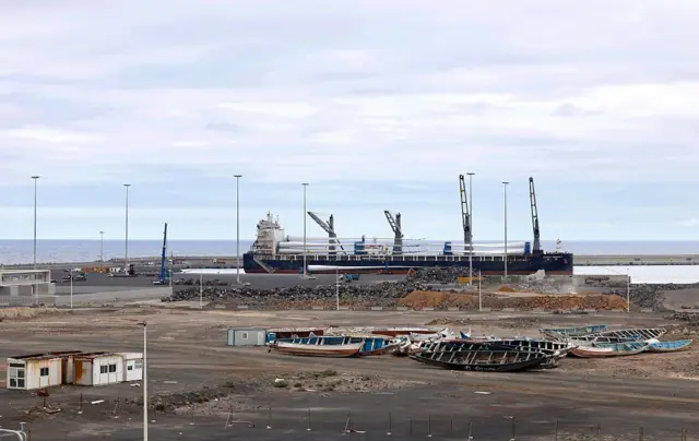 Un gran buque de carga se observa detrás de embarcaciones de migrantes apiladas en el puerto de Granadilla de Abona, en la isla de Tenerife, en el archipiélago de las Islas Canarias, España, el 6 de mayo de 2026. 