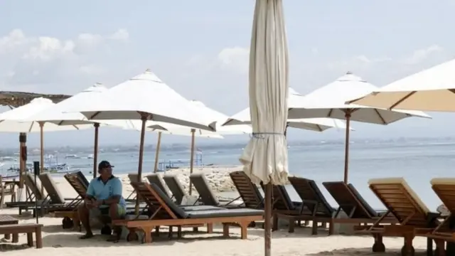 Seorang karyawan tempat wisata di pantai Sanur, Bali, menunggu tamu.