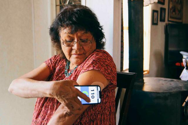 A senior aged Indigenous Navajo woman, checking her blood glucose level with a smartphone application