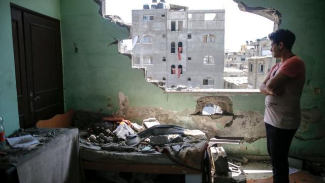 Um homem palestino inspeciona os danos em seu quarto após ataques aéreos israelenses em seu bairro no campo de refugiados de Jabalia, Faixa de Gaza do Norte em 20 de maio de 2021