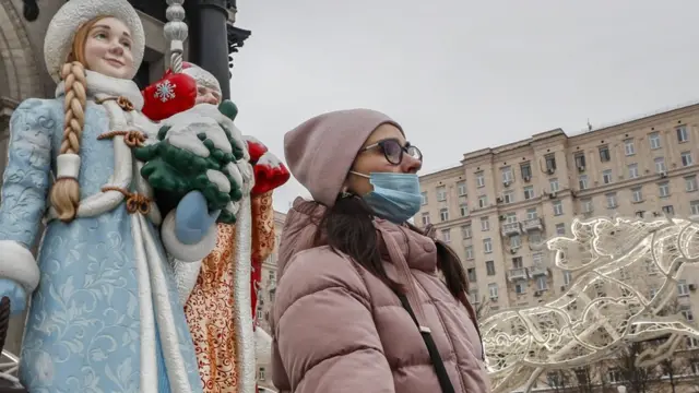 Женщина в маске на фоне новогодних украшений в Москве