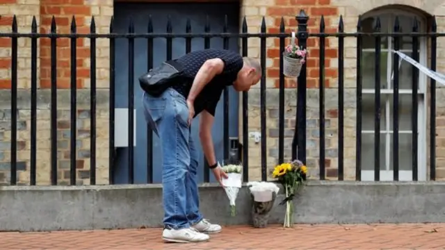 Un homme dépose une gerbe de fleurs sur les lieux du drame