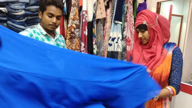 পোশাক পছন্দ করছেন বাংলাদেশ থেকে যাওয়া এক তরুণী।