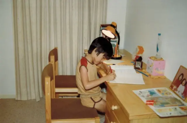 Terence Tao sentado en un escritorio escribiendo sobre un cuaderno