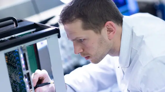 Empleado de Thales vestido con bata de laboratorio trabajando en el desarrollo de radares de vigilancia y defensa aérea en las instalaciones de Thales en Limours.