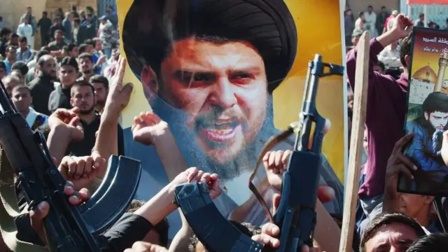 Armed supporters of al-Sadr carrying a placard with his picture