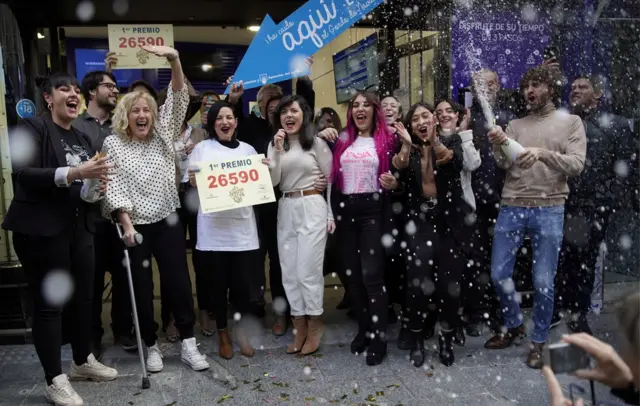 Los dueños y empelados de la tienda Doña Manolita en Madrid celebran la venta del número ganador del primer premio