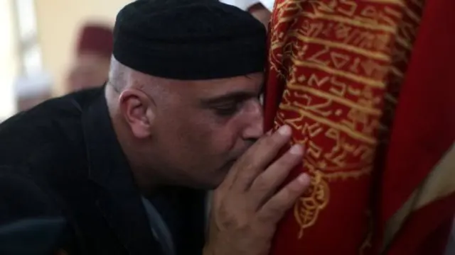 أحد المصلين السامريين وهو يقبل صندوقا يحتوي على لفائف التوراة المقدسة