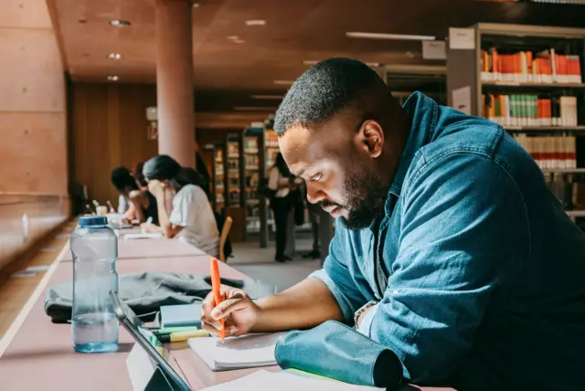 Homem fazendo anotação no cadernopadroes arbetybiblioteca