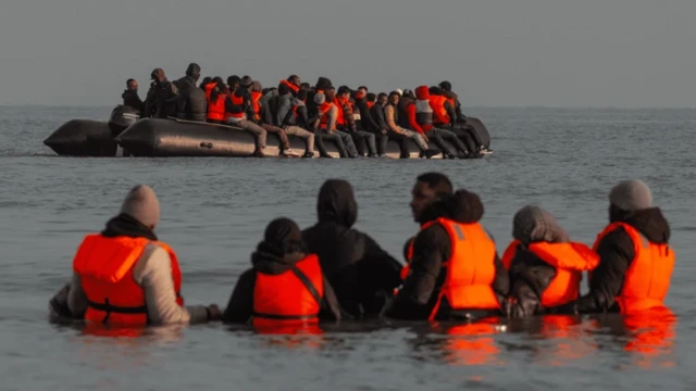 تعدادی پناهجو با جلیقه نجات نارنجی رنگ، در قایق و در آب