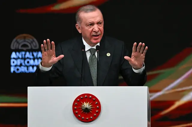 Cumhurbaşkanı Erdoğan, Antalya Diplomasi Forumu'nda kürsüde konuşurken iki elini birden kaldırmış
