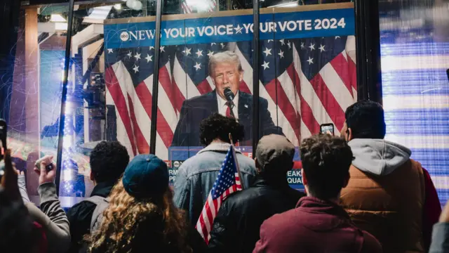 Gente mirando a Trump en una pantalla