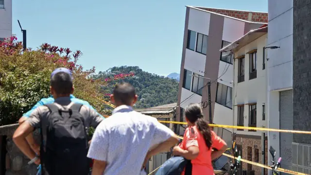 Cuatro personas de espaldas y desenfocadas observan un edificio dañado por el terremoto en Manizales, Caldas, Colombia, el lunes 10 de agosto de 2026. (Foto de Giovanny Galvez / AFP vía Getty Images)