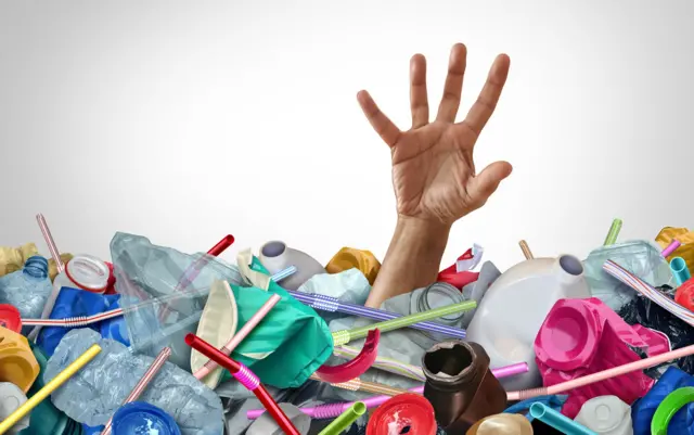 Рука людини стирчить з купи різнокольорових пластикових виробів