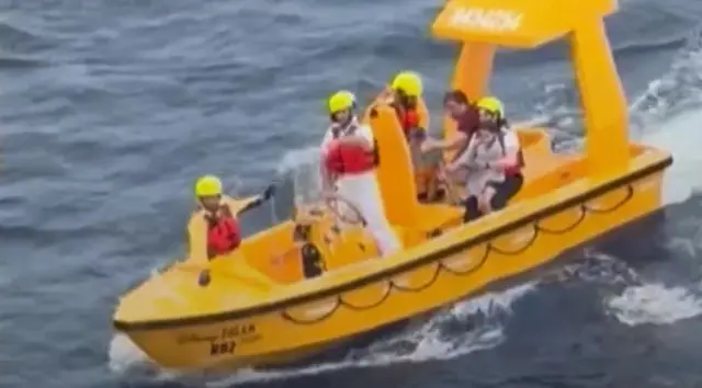 Barco amarelo com cinco pessoas a bordo, entre elas uma criança