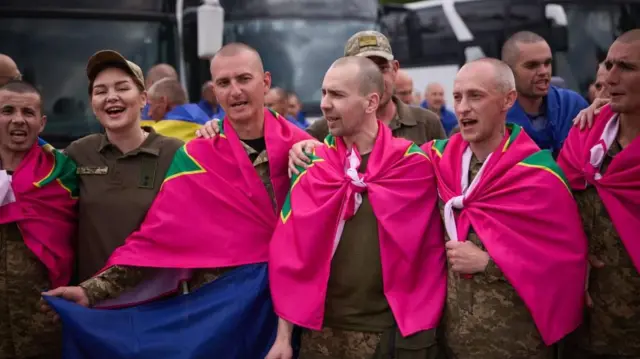 Imfungwa zarekuwe n'Uburusiya zitonze umurongo, ziteye amabendera y'iroza, icyatsi kibisi n'umuhondo, y'urwego rw'abarinda umupaka rwa Ukraine 