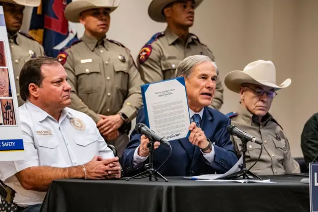 El zar fronterizo de Texas, Mike Banks, izquierda, y el director del Departamento de Seguridad Pública de Texas, Steve McCraw, derecha, observan cómo el gobernador Greg Abbott firma una proclamación que declara a la pandilla venezolana Tren de Aragua (TdA) una organización terrorista internacional durante una conferencia de prensa en la sede regional del DPS del Sureste de Texas en Houston. (Kirk Sides/Houston Chronicle vía Getty Images)