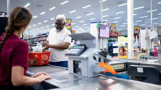 Homem passando em caixa de supermercado
