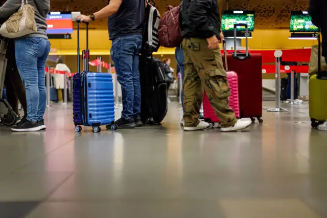 Pasajeros en fila con sus maletas en el aeropuerto de Bogotá.