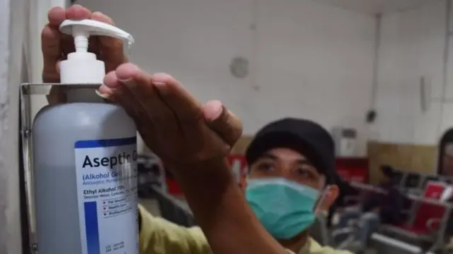 Calon penumpang Kereta Api membersihkan tangannya menggunakan hand sanitizer yang tersedia di Stasiun KA Madiun, Jawa Timur, Selasa (03/03).