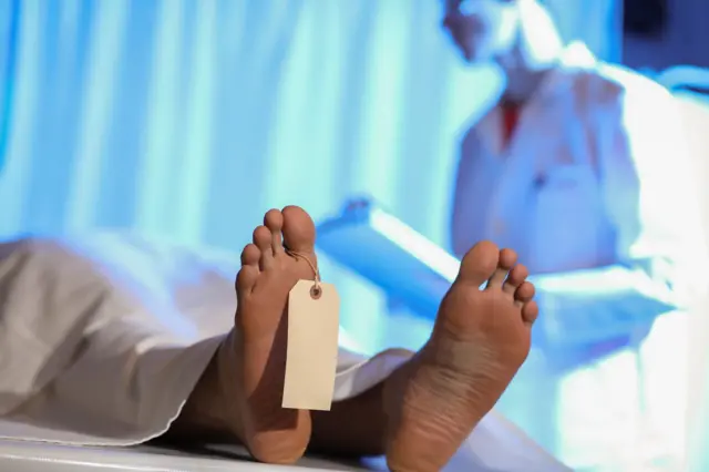 Seorang dokter sedang memeriksa jenazah.