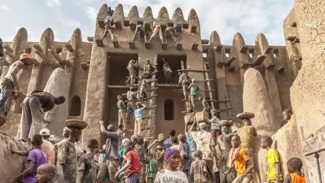 Des personnes participent au crépissage à la Grande Mosquée de Djenné