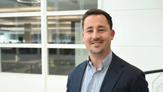 Phil Bearpark, vestido con una chaqueta de traje azul, sonríe y mira a la cámara.