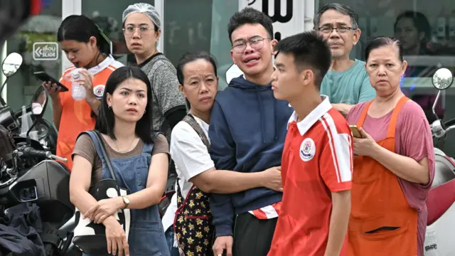 人群聚集在泰國首都曼谷以北的暖武里府挽粿縣（Bang Kruai）的帖詩琳暖武里學校外，一位年長女士抱著痛哭中的一位年輕男生（7/8/2026）