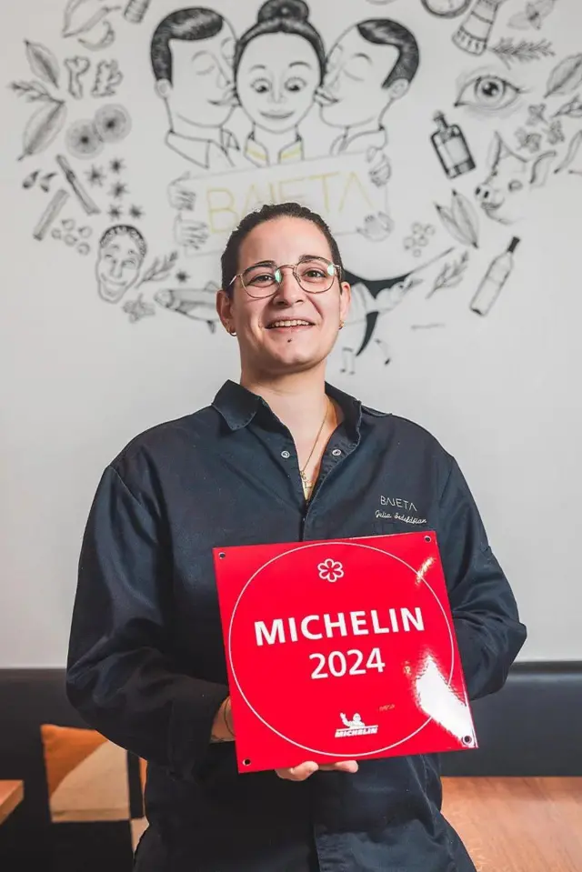 Chefe segura uma placa vermelha escrito Michelin 2024. 