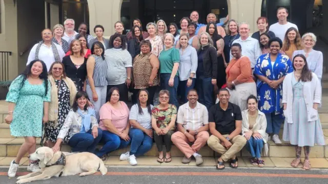 Echipa centrului de consiliere de la Universitatea Stellenbosch din Cape Town – aproximativ 45 de membri, plus un câine, care zâmbesc și par relaxați.