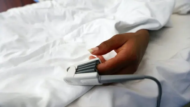 Un oxymètre de pouls est fixé au doigt d'un patient, pour surveiller l'apport en oxygène dans le corps, dans les cliniques de l'EHA à Abuja, au Nigeria, le 14 janvier 2021