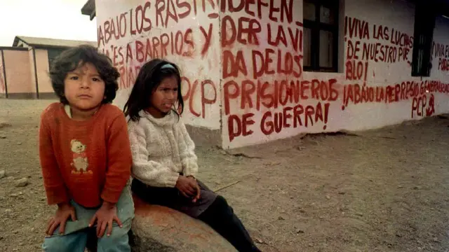 niños frente a una casa pintada con carteles.