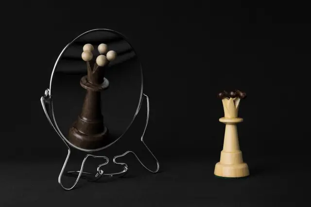 Concept image: white queen sees black queen in the mirror