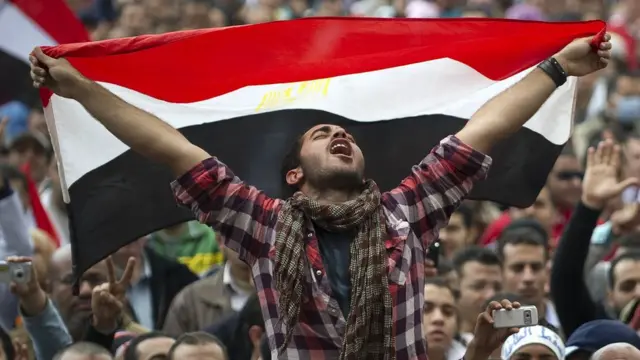 متظاهر يحمل علم مصر في ميدان التحرير بالقاهرة عام 2011