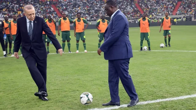 Le président turc Erdogan (à gauche) et le président sénégalais Macky Sall (à droite) sepassent le ballon sur la pelouse du stade Abdoulaye Wade lors de son inauguration