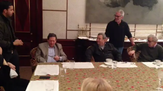 يظهر باراك وإبستين ضمن مجموعة رجال يجلسون على طاولة عليها أوراق ومياه وفناجين، ويتحدثون لبعضهم البعض