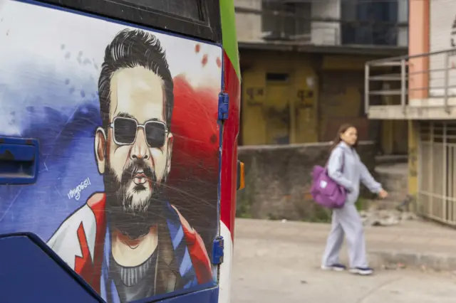 एउटा यात्रुवाहक बसमा पेन्ट गरिएको बालेन शाहको तस्बिर नजिकैबाट हिँड्दै एक महिला