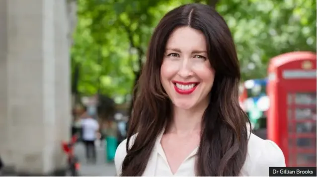 Dr Gillian Brooks agaragara aseka ,yambaye ishati y'umweru